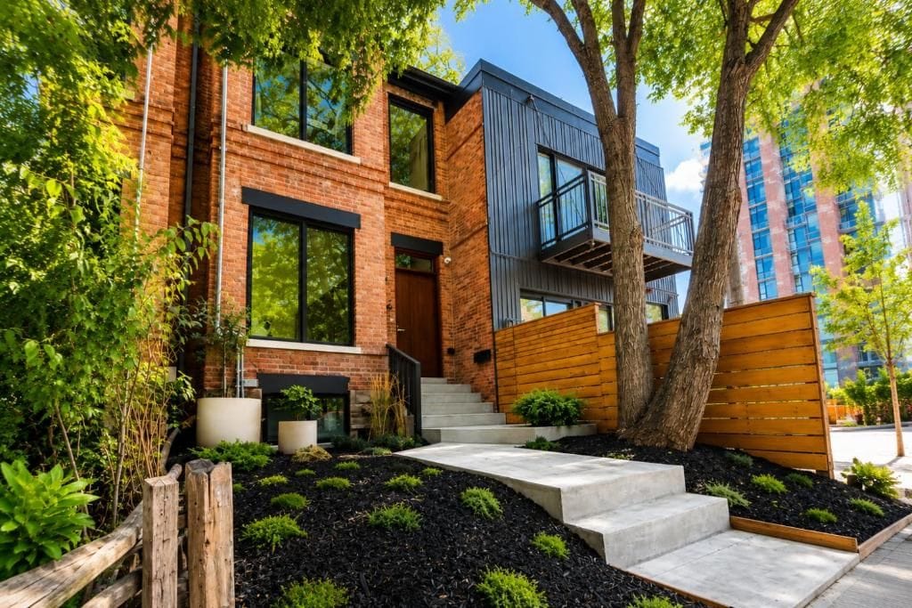 A modern building with a brick facade, large windows, and a wooden deck.