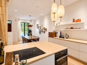 A modern kitchen with a central island, built-in appliances, and pendant lighting. - Sumach House (Toronto)