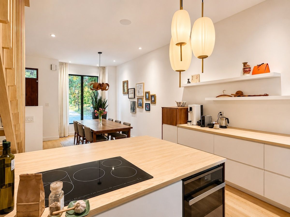 A modern kitchen with a central island, built-in appliances, and pendant lighting.