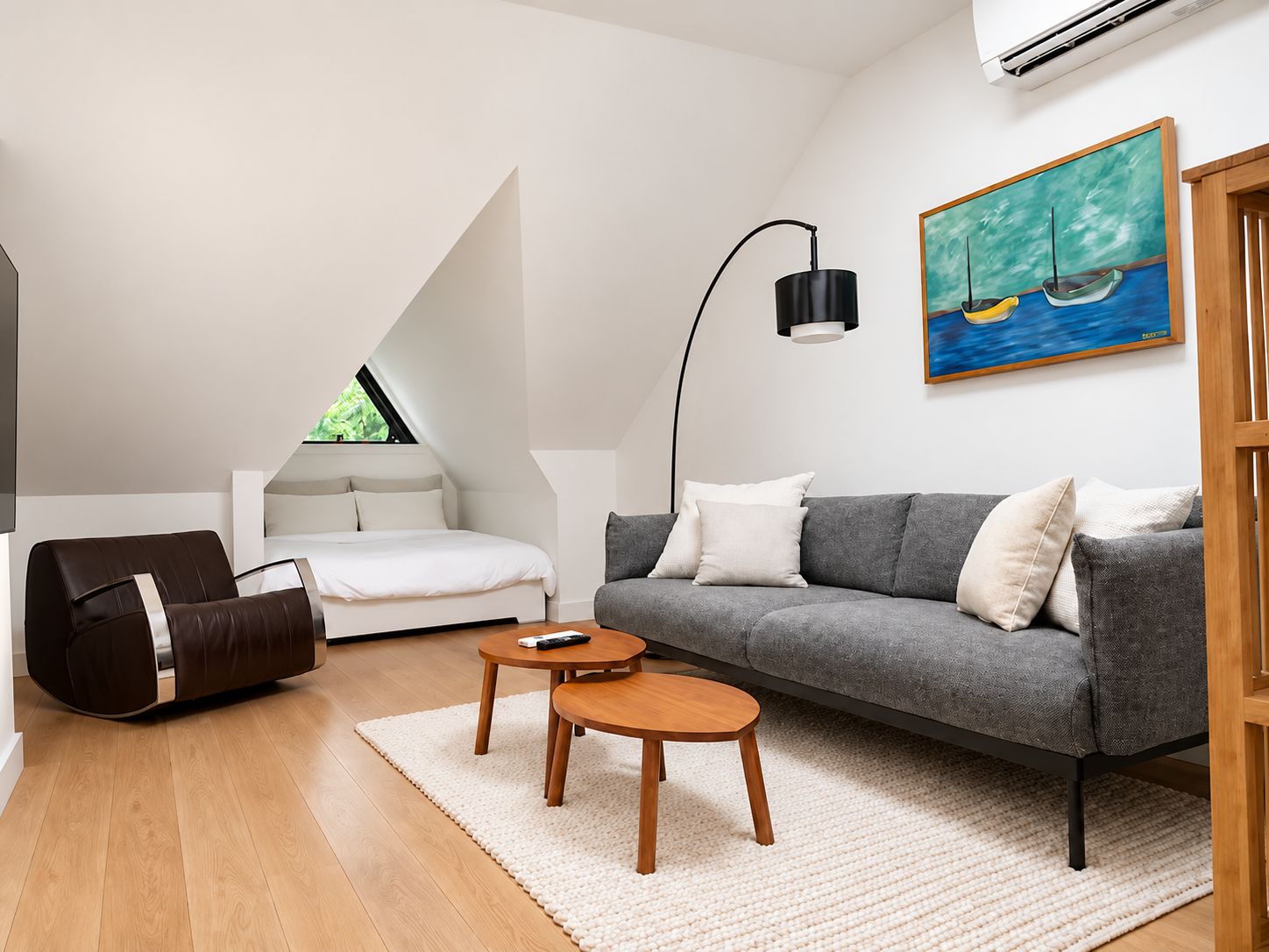 Un salon moderne avec un canapé, une table basse, un fauteuil poire et un tableau accroché au mur.