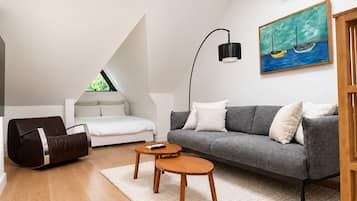 Un salon moderne avec un canapé, une table basse, un fauteuil poire et un tableau accroché au mur.