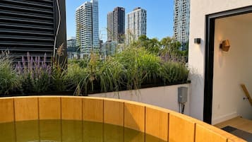 A rooftop garden with a water feature, surrounded by tall buildings.