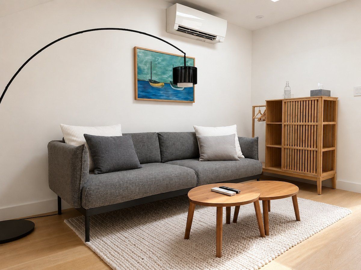 A modern living room with a grey sofa, a wooden coffee table, a painting of a boat, and a black floor lamp.