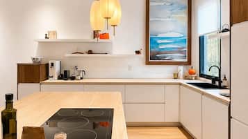 A modern kitchen with a central island, pendant lighting, and a large window.