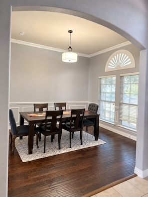 A dining room with a dark wooden table, six chairs, a patterned rug, and a ceiling light fixture. - Spacious Furnished 3BR/2.5BA North Dallas Home - Office Space & Fast Wifi (Dallas)