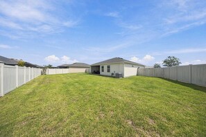 A residential property with a fenced backyard, a single-story house, and a clear sky. - Brand-New 3BR · Golf Cart · Fenced Yard · Eastport (Sumterville)