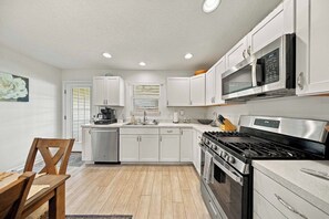 Una cocina moderna con armarios blancos, electrodomésticos de acero inoxidable y una mesa de comedor de madera.