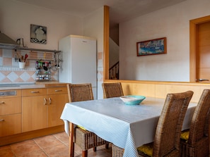 A kitchen with wooden cabinets, a white refrigerator, and a dining table with wicker chairs. - House with garden near the beach - 6 guests (Creixell)