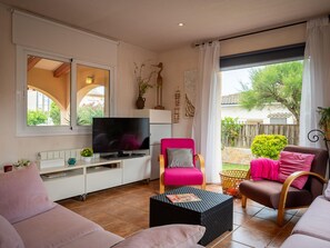 A living room with a flat-screen TV, a pink armchair, a brown sofa, and a wicker coffee table. - House with garden near the beach - 6 guests (Creixell)