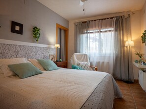 A bedroom with a bed, a chair, a nightstand, a lamp, and a window with curtains. - House with garden near the beach - 6 guests (Creixell)