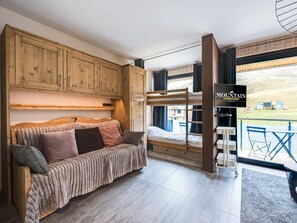 A bunk bed with a television, wooden cabinets, and a sofa in a room with a view. - Functional studio, mountain view - 4 guests (La Toussuire)