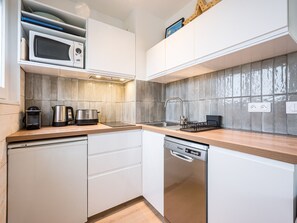 A modern kitchen with white cabinets, a stainless steel dishwasher, a microwave, and a kettle. - Renovated studio, mountain view - 4 guests (La Toussuire)