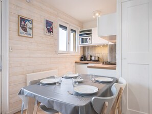 A dining area with a table set for four, a microwave, and a coffee maker on the counter. - Renovated studio, mountain view - 4 guests (La Toussuire)