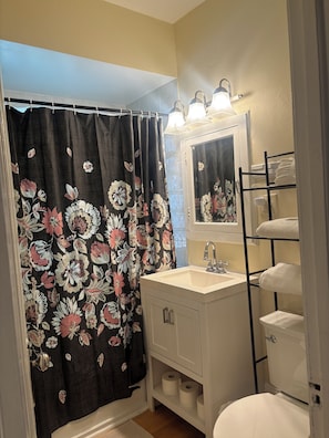 Un baño con cortina de ducha, lavabo, inodoro y un perchero para toallas.