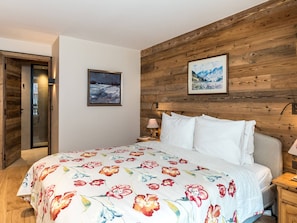Ein Schlafzimmer mit einem Holz-Kopfteil, einem Bett mit weißer Bettwäsche, einem Nachttisch und zwei gerahmten Bildern an der Wand.