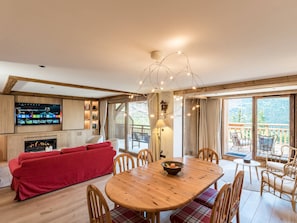 Ein modernes Wohnzimmer mit einem roten Sofa, einem Holzesstisch und einem an der Wand befestigten Fernseher.