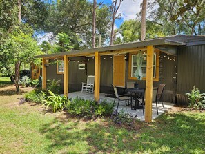 A wooden deck with outdoor seating and string lights. - Welcome to Gator Bait Getaway! Tucked among the pines near Salt Springs. (Fort McCoy)