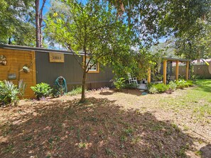 A backyard with a wooden fence, a tree, and a covered patio area. - Welcome to Gator Bait Getaway! Tucked among the pines near Salt Springs. (Fort McCoy)
