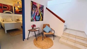 A modern living room with a sofa, a chair, a small table, and a painting on the wall.