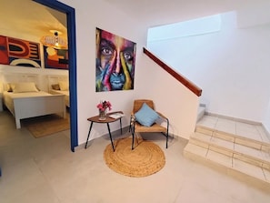 A modern living room with a sofa, a chair, a small table, and a painting on the wall.