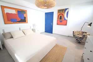 Um quarto com uma cama, uma porta azul e obras de arte nas paredes.