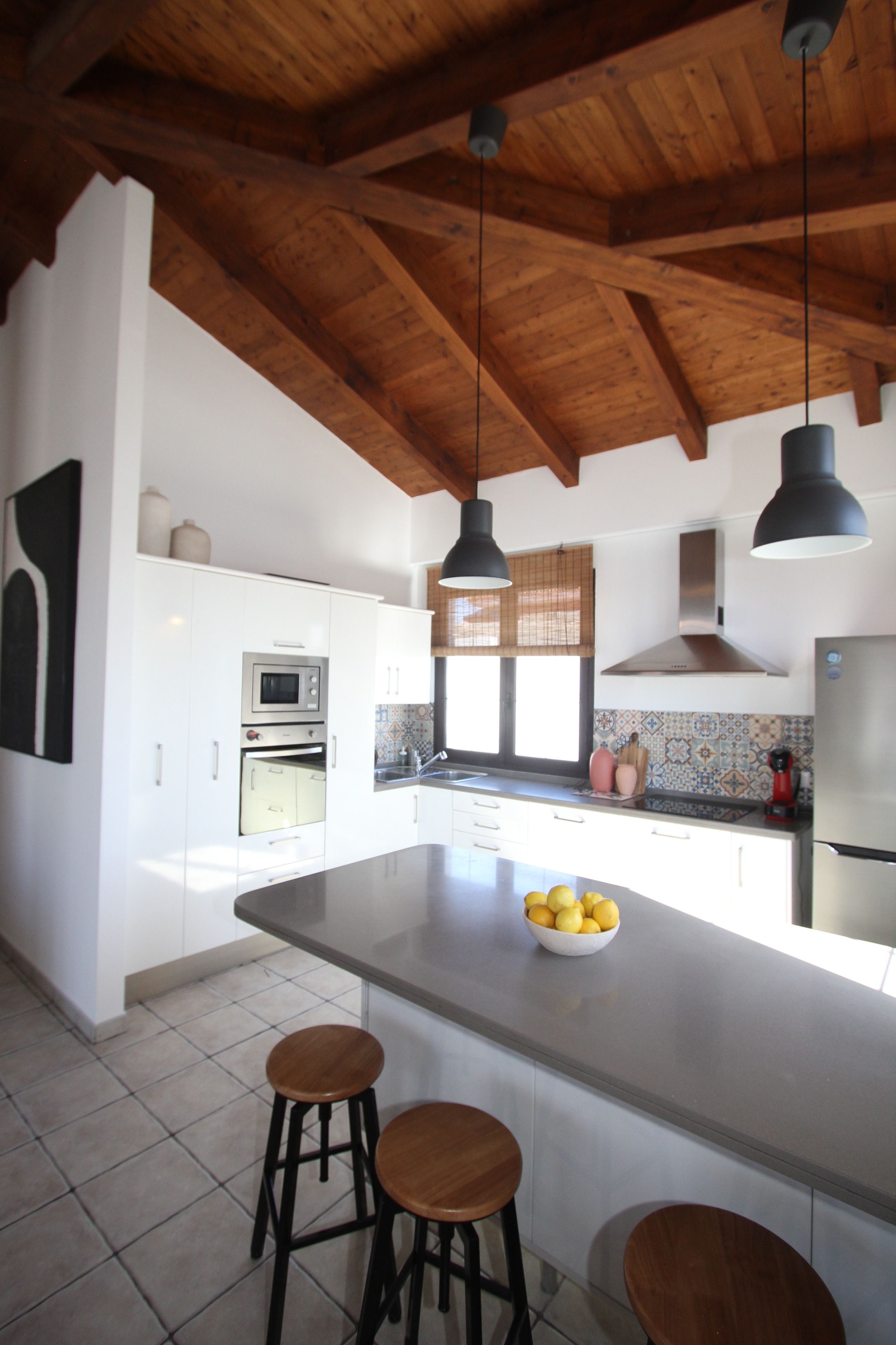 Una cucina con un'isola grande, sgabelli di legno, un forno a microonde e un frigorifero.