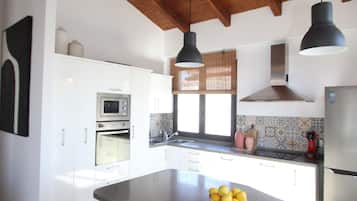Una cucina con un'isola grande, sgabelli di legno, un forno a microonde e un frigorifero.