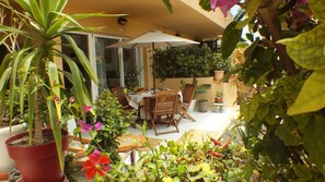 An outdoor patio area with a table and chairs, surrounded by potted plants and a large umbrella. - Casa Dan "Pool Views & Excellent Private Garden Terrace" (Corralejo)