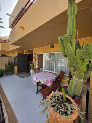 A patio area with a table covered by a polka dot tablecloth, surrounded by chairs, and a large cactus plant. - Casa Dan "Pool Views & Excellent Private Garden Terrace" (Corralejo)