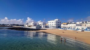 A coastal town with clear waters, sandy beach, and white buildings. - Casa Dan "Pool Views & Excellent Private Garden Terrace" (Corralejo)