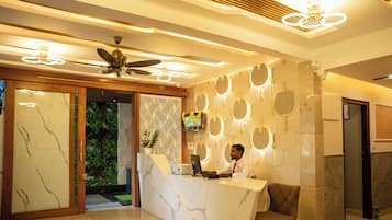 Una recepción con diseño moderno, un ventilador de techo y una pared decorativa con motivos circulares.