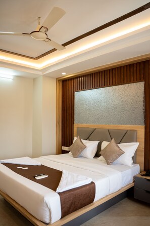 Habitación de hotel con una cama, mesita de noche, teléfono y ventilador de techo.