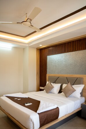 Una habitación de hotel moderna con una cama grande, cabecera de madera y un ventilador de techo.