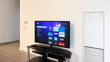 Un televisor de pantalla plana montado sobre un soporte negro, con un control remoto encima.