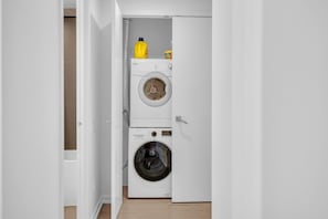 A laundry room with a washing machine and dryer, a yellow detergent bottle, and a detergent box. - StayToronto - Downtown Peter Suites (Toronto)