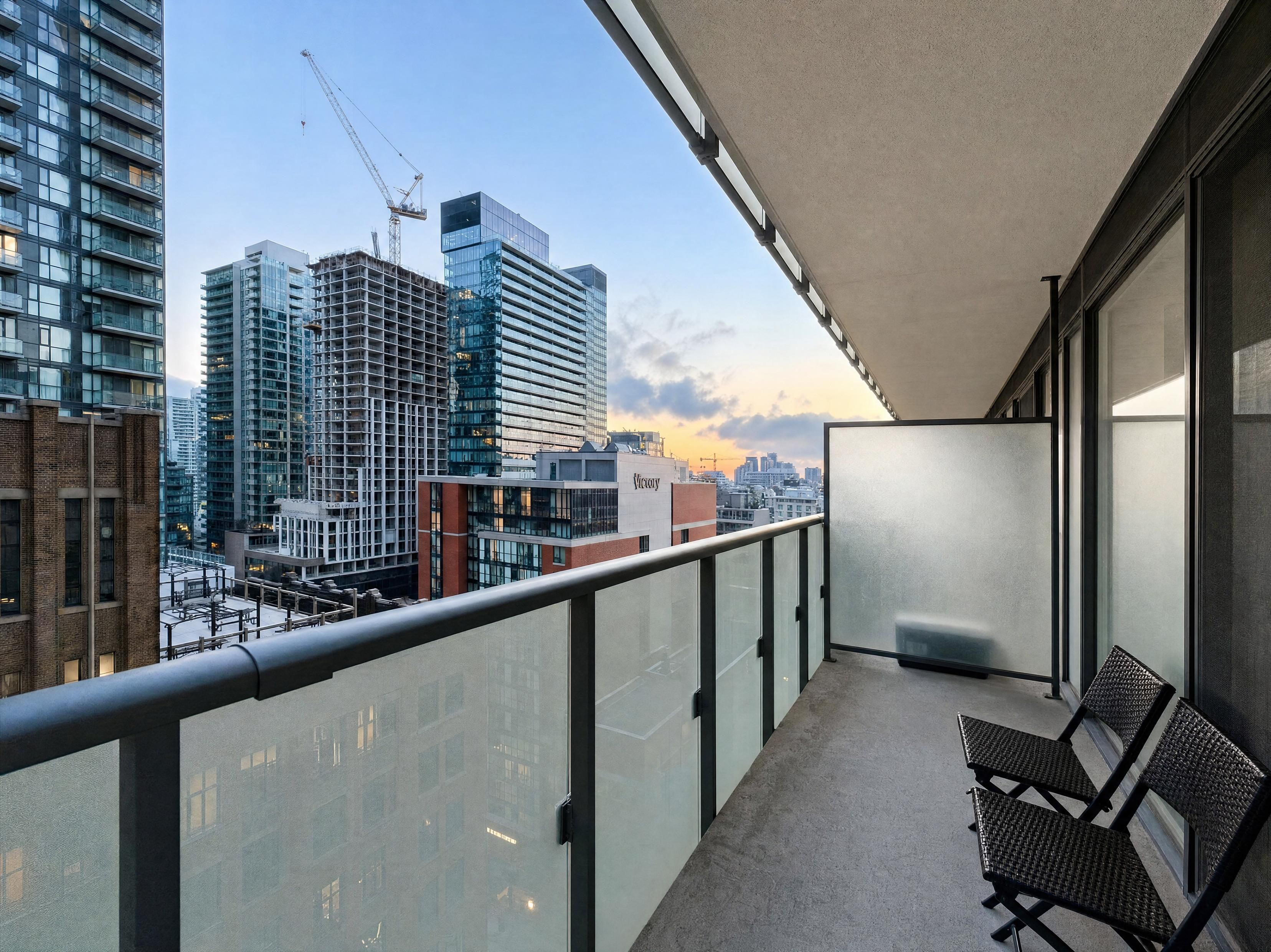 Een balkon met uitzicht op een stadsbeeld, inclusief moderne gebouwen en een bouwkraan.