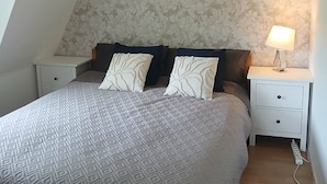 A bedroom with a bed, two nightstands, a lamp, and a patterned wallpaper. - Charming Countryside Apartment Near Koping - Pet Friendly! (Köping)
