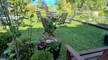 Ein Garten mit Tisch und Stühlen, umgeben von verschiedenen Pflanzen und Blumen.