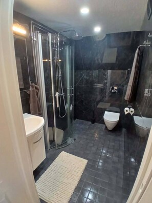 Un baño moderno con cabina de ducha de vidrio, inodoro y lavamanos.