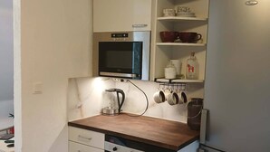 A compact kitchen with a microwave, oven, and a refrigerator. - Charming Countryside Apartment Near Koping - Pet Friendly! (Köping)