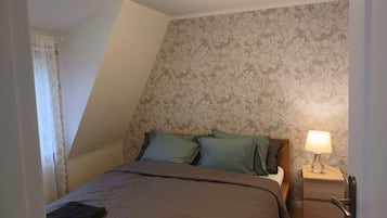 Ein Schlafzimmer mit einem Bett, Kissen, einem Nachttisch und einer Lampe.