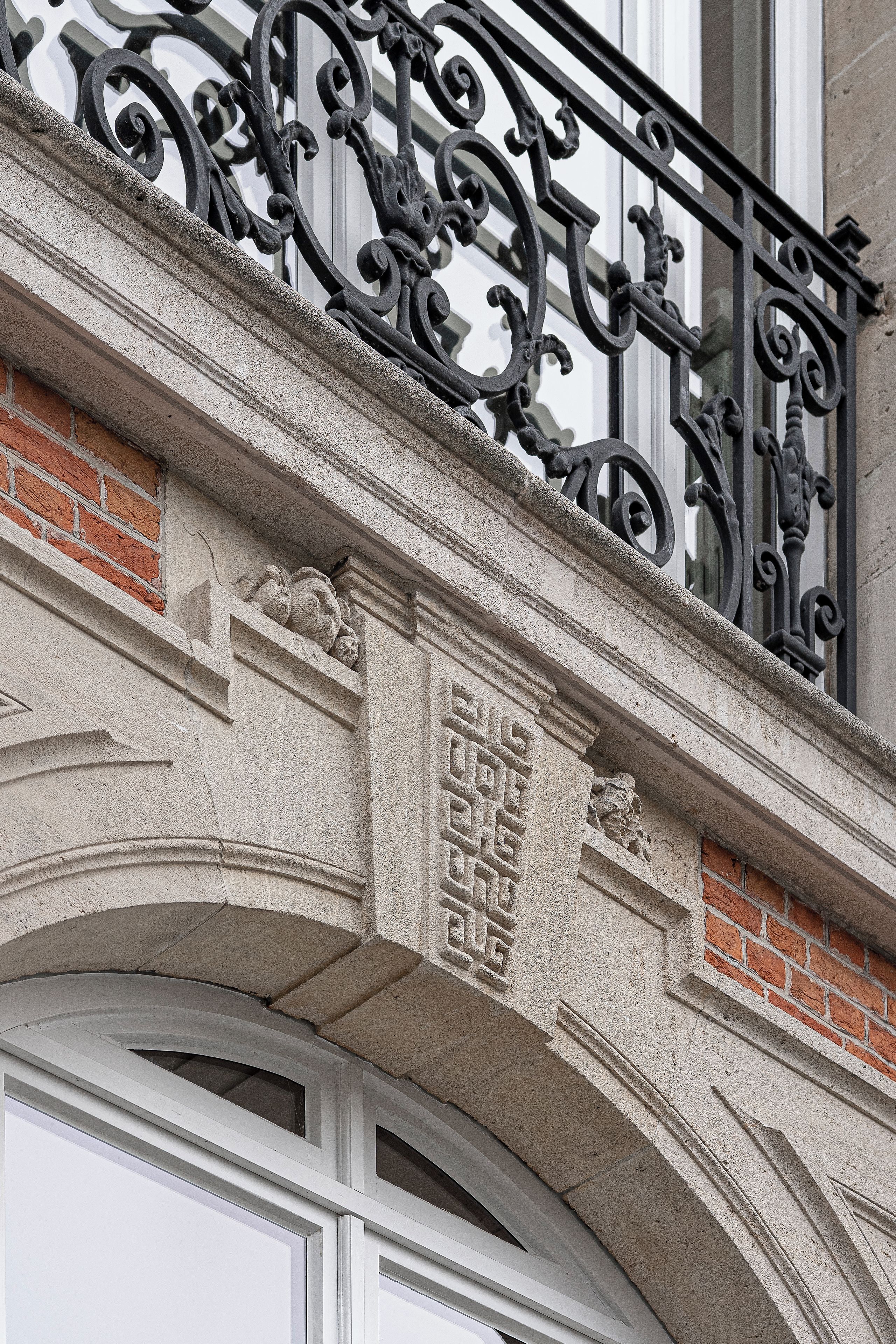Une façade d’immeuble ornée d’un balcon en fer forgé décoratif et d’un cadre de fenêtre en pierre.