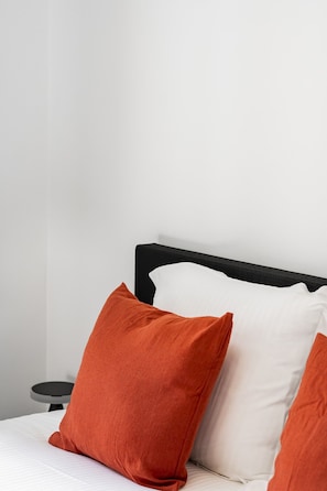 A bed with a black headboard, white and orange pillows, and a small round table with a black surface. - Boutique Townhouse Suite | Bruges Centre (Brugge)