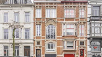 Een rij van herenhuisachtige woningen met drie verdiepingen, een garagepoort in het midden en auto's langs de straat.