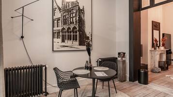 Un coin repas comprenant une table ronde, des chaises, un radiateur noir et un luminaire fixé au mur.