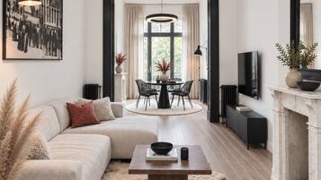 Un salon moderne avec un canapé, une table basse et une cheminée. On y trouve également un coin repas avec une table et des chaises, ainsi qu’une grande fenêtre avec des rideaux.