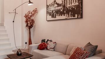 Un salon moderne avec un canapé, une lampe sur pied, un vase et une photographie encadrée accrochée au mur.