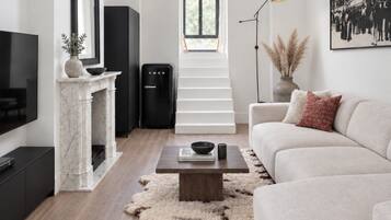 Een moderne woonkamer met een open haard, een bank, een salontafel en een trap naar een verdieping erboven.