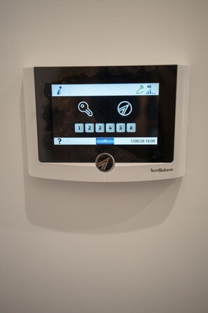Ein an der Wand montiertes elektronisches Gerät mit Tastenfeld und Bildschirm, der ein Datum und eine Uhrzeit anzeigt.
