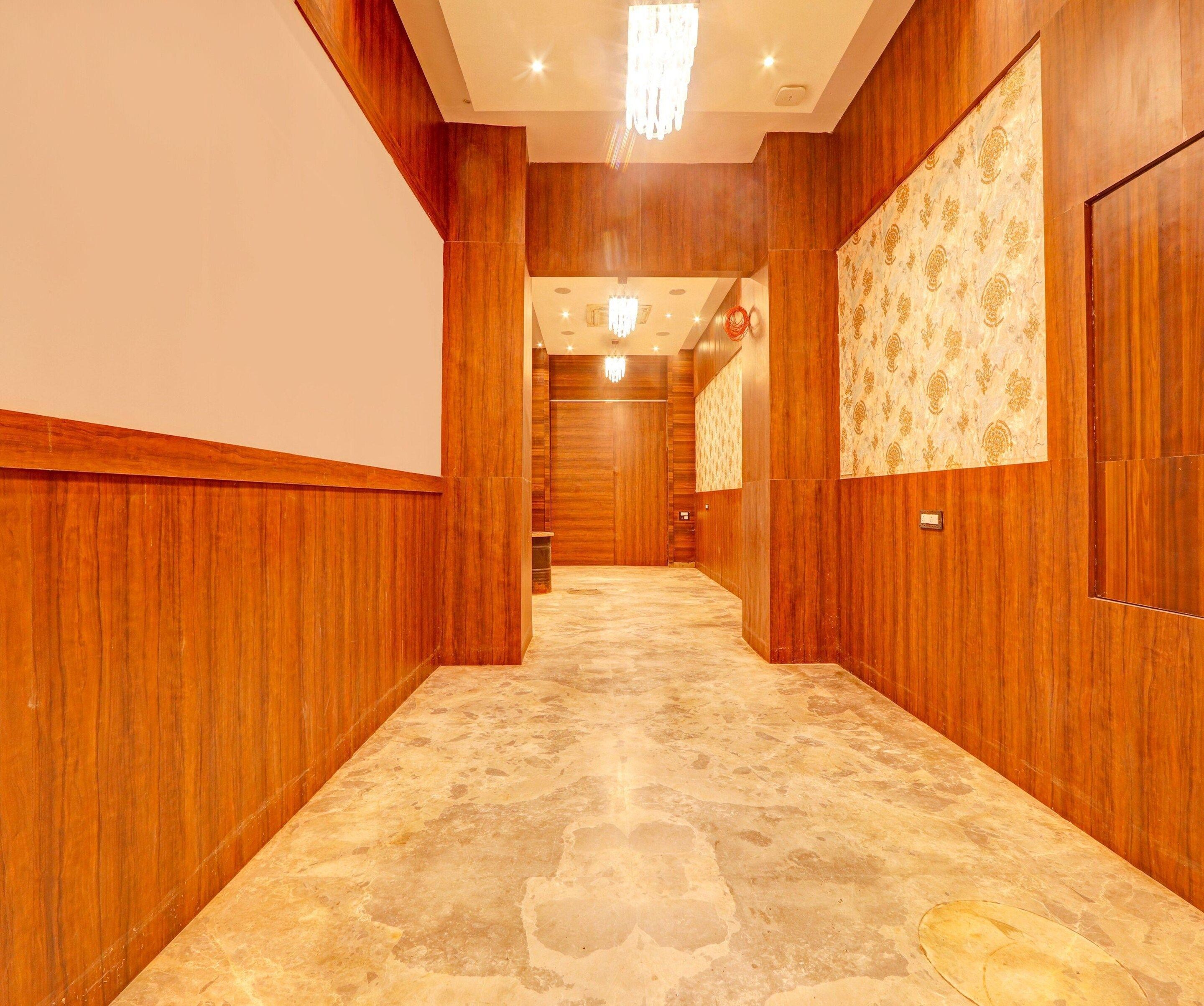Un corridoio d'hotel con pannelli in legno, carta da parati decorata e pavimento in marmo.